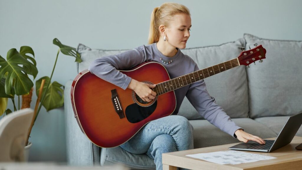 Une fille qui apprend la guitare seule avec son ordinateur