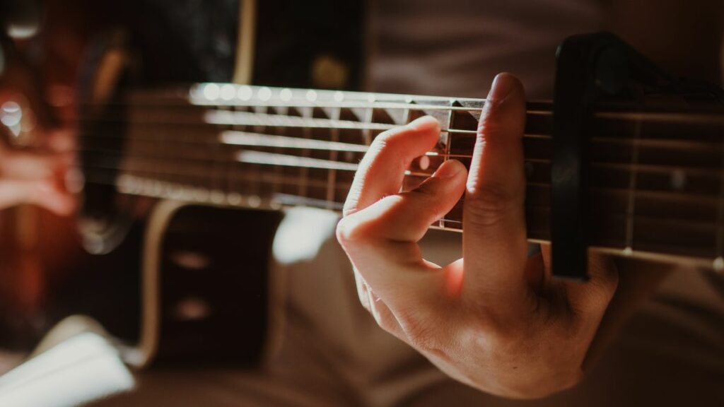 Homme faisant un accord barré à la guitare