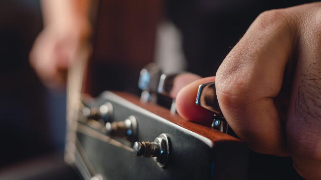 Un homme qui accorde sa guitare