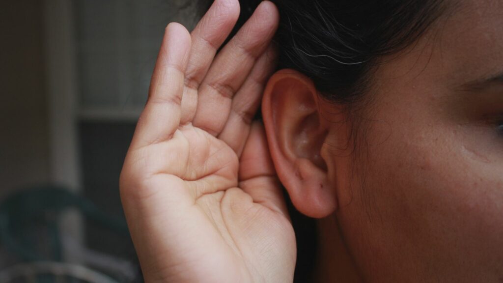 Femme mettant sa main derrière l'oreille pour écouter