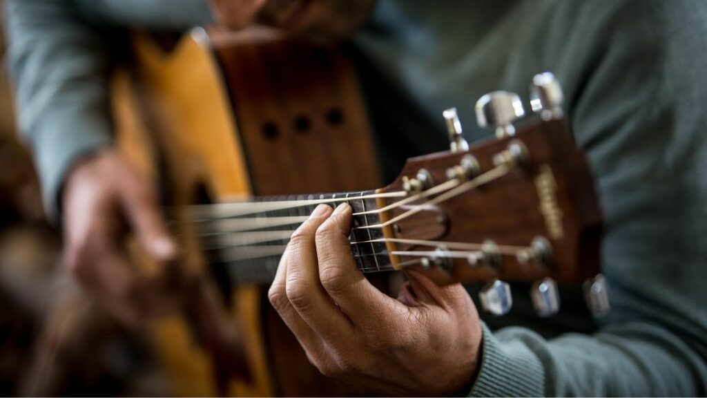 Un homme en train d'improviser sur une guitare acoustique